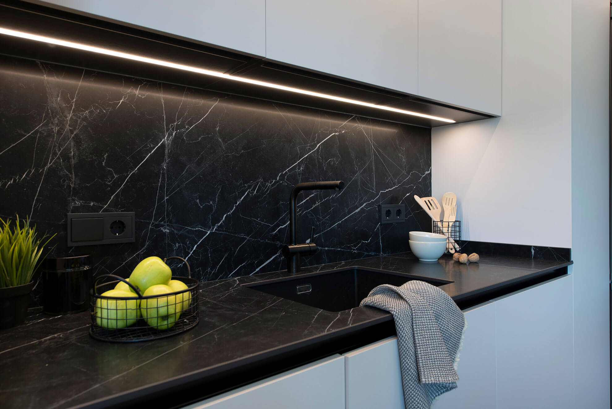 Encimera y salpicadero de porcelánico negro con veta blanca y alguna veta dorada. es el modelo Sapienstone dark marquina, que imita al reconocido mármol